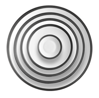 Five Soie Tressée Black dinnerware plates by L'Objet, made of white Limoges porcelain with black patterned rims, are stacked concentrically from largest to smallest and viewed from above against a white background.