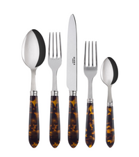 The Sabre Tortoise Flatware 5 Piece Setting features 18/10 stainless steel with brown tortoiseshell-patterned acrylic handles and includes a soup spoon, dinner fork, knife, salad fork, and teaspoon arranged upright side by side.