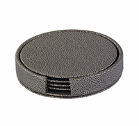 The Bodrum Skate Coaster Set of 4 includes round, textured dark gray phthalate-free vinyl coasters with a holder featuring a front opening that reveals the matching set inside.