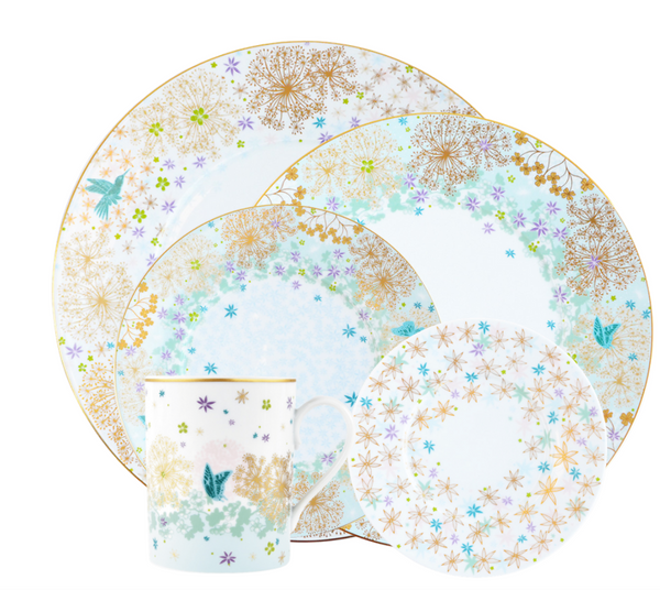 Bernardaud’s Fèerie By Michael Cailloux dinnerware set includes plates and a mug adorned with gold, blue, and green dandelion and starburst patterns plus a teal butterfly motif from the Fèerie Dinner Collection.
