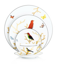 The Bernardaud Aux Oiseaux Dinnerware set in white Limoges porcelain features gold branch patterns with colorful birds and butterflies. Includes dinner plate, salad plate, dessert plate, and teacup with saucer.