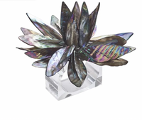 The Shell Flower Napkin Ring Set of 4 by Kim Seybert features iridescent, shell-like petals layered in a floral design atop a clear acrylic base, adding elegance and style to any table setting.