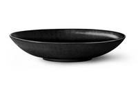 A shallow, round, matte black ceramic bowl with a wide rim from L'Objet's Terra Iron Dinnerware collection, shown against a white background.
