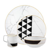 Vista Alegre’s Carrara by Coline Le Corréa Dinnerware set features a large plate, small plate, mug, and bowl in porcelain with gold rims, Carrara marble pattern, and bold black geometric triangles.