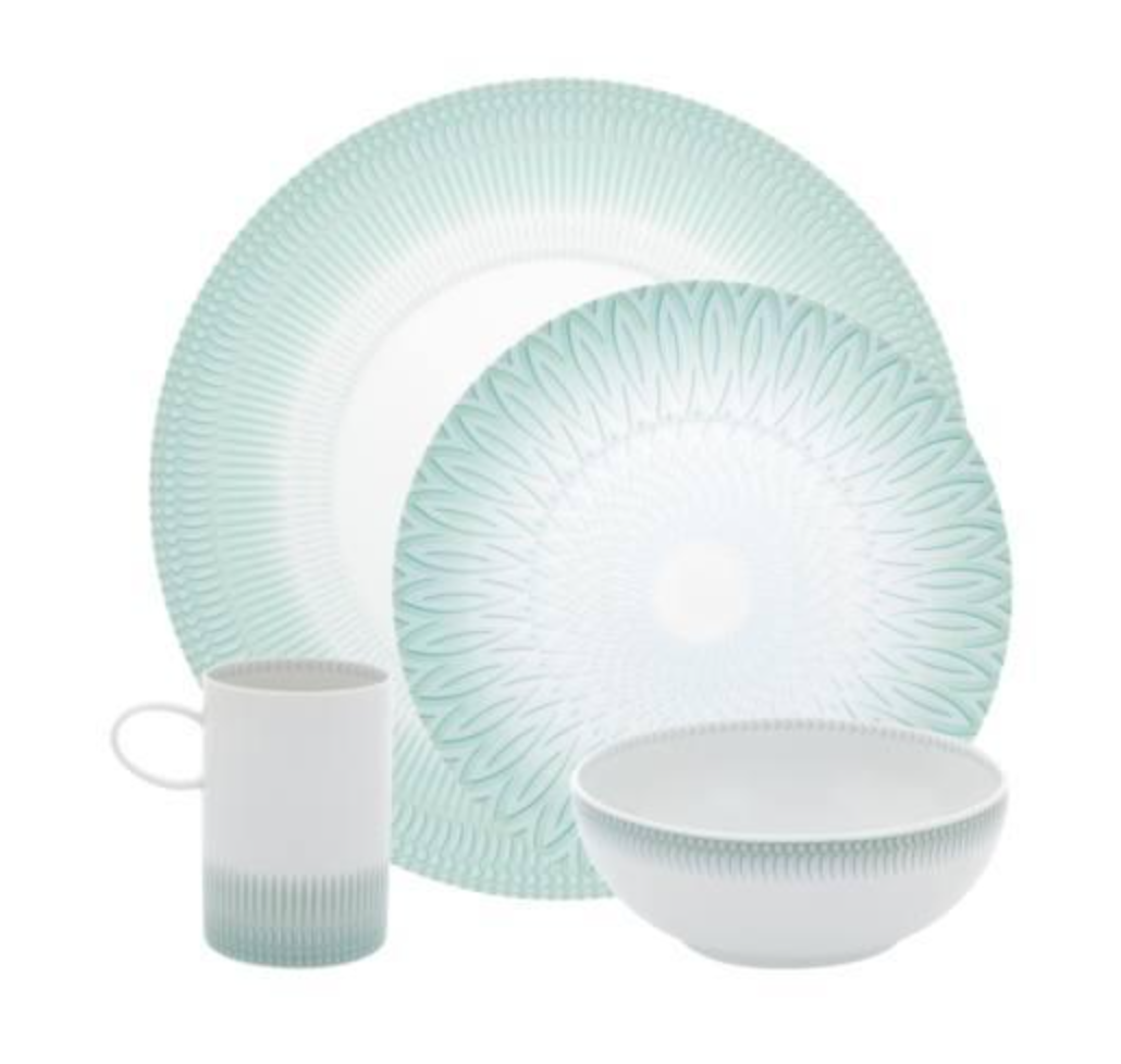 The Venezia Dinnerware set by Vista Alegre features four porcelain pieces—a dinner plate, salad plate, bowl, and mug—with a white base and light green geometric patterns.