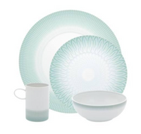 The Venezia Dinnerware set by Vista Alegre features four porcelain pieces—a dinner plate, salad plate, bowl, and mug—with a white base and light green geometric patterns.