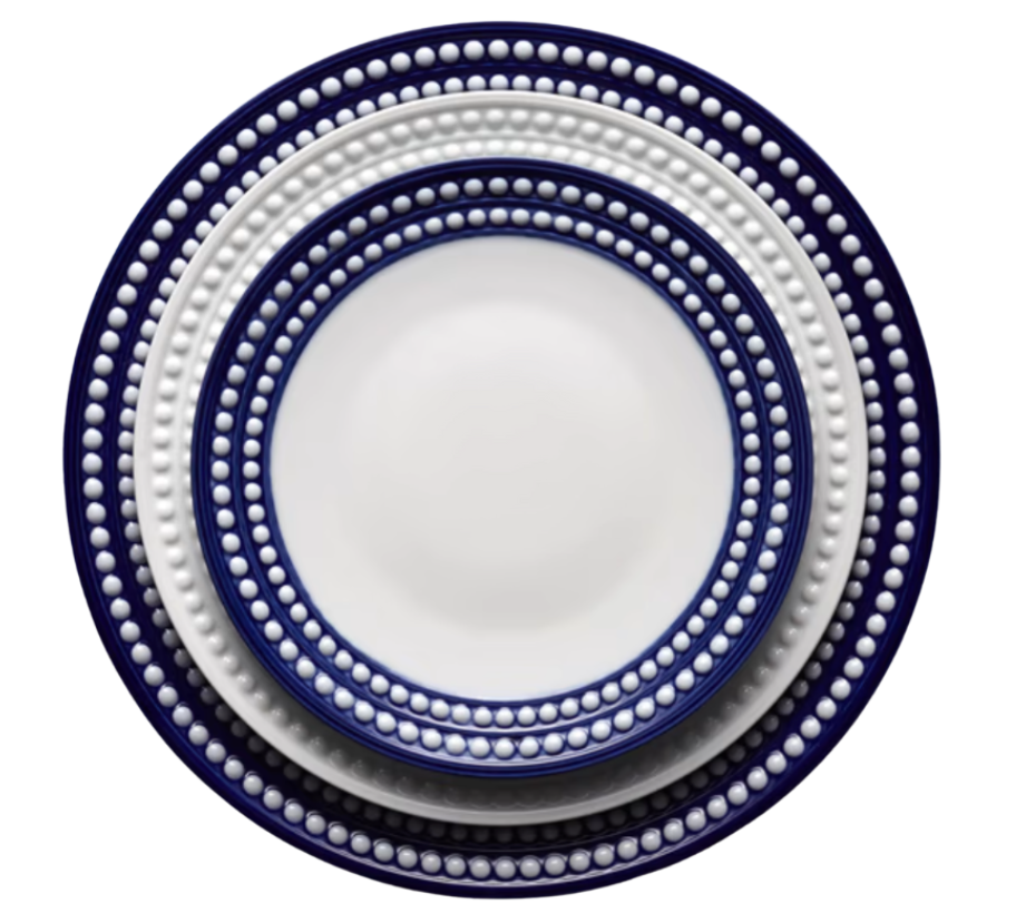 The L'Objet Perlèe Blue Dinnerware showcases three stacked round plates with a white center, dark blue edge, and raised white dot border—an elegant way to enhance your blue and white table setting.