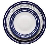 The L'Objet Perlèe Blue Dinnerware showcases three stacked round plates with a white center, dark blue edge, and raised white dot border—an elegant way to enhance your blue and white table setting.