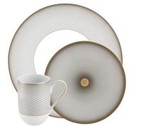 The Raynaud Oskar Dinnerware set includes a mug, dinner plate, and salad plate, crafted from Limoges porcelain with gold rims and gray geometric designs.