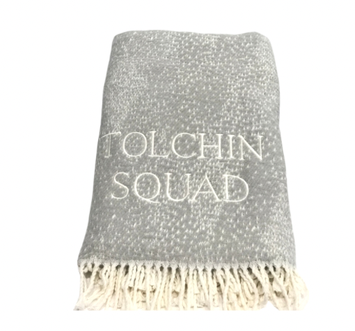A Soft Idea Personalized Throw Blanket: folded gray throw with white speckles, fringe, and "TOLCHIN SQUAD" embroidered in white on the front.