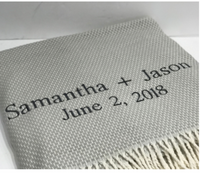The A Soft Idea Personalized Throw Blanket is a light gray woven throw with fringed edges, embroidered in dark thread with "Samantha + Jason" and "June 2, 2018".