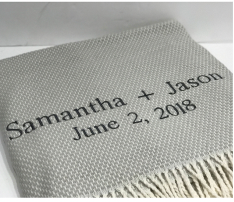 The A Soft Idea Personalized Throw Blanket is a light gray woven throw with fringed edges, embroidered in dark thread with "Samantha + Jason" and "June 2, 2018".