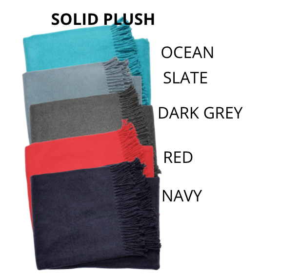 Five folded, fringed Personalized Throw Blankets by A Soft Idea in Ocean (turquoise), Slate (light grey), Dark Grey, Red, and Navy. Bold heading: SOLID PLUSH—ideal for cozy, stylish comfort and perfect for personalizing.
