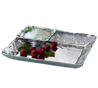 The Beatriz Ball Linda Chip & Dip Set features a shiny, divided metal tray holding a square bowl with white dip and garnish, alongside raspberries and mint leaves in the larger compartment.