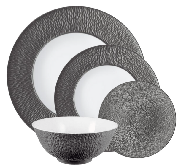 The Raynaud Mineral Irise Dinnerware Dark Grey set features textured dark gray exteriors and smooth white interiors. Made in France, it includes two plates, one smaller plate, and a bowl, all displayed overlapping each other.