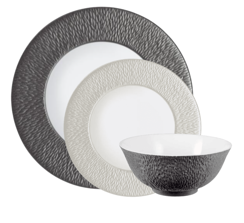 Raynaud’s Mineral Irise Dinnerware Pearl Grey features three Limoges porcelain pieces: a large dark gray plate, a smaller light gray plate, and a coordinating dark gray and white bowl, all with pebbled surfaces.