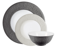 Raynaud’s Mineral Irise Dinnerware Pearl Grey features three Limoges porcelain pieces: a large dark gray plate, a smaller light gray plate, and a coordinating dark gray and white bowl, all with pebbled surfaces.