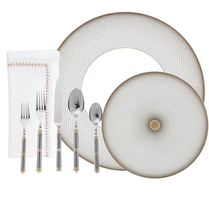 A table set with Raynaud's Oskar Dinnerware: one large and one small patterned porcelain plate, a stitched cloth napkin, plus silver cutlery—knife, fork, spoon, and dessert spoon—all with striped handles and gold accents.