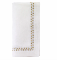 The Pearls Napkin Gold Set of 4 by Bodrum features neatly folded white linen napkins, each adorned with two rows of delicate gold embroidered dots in an L-shaped border—an elegant touch to any table setting.