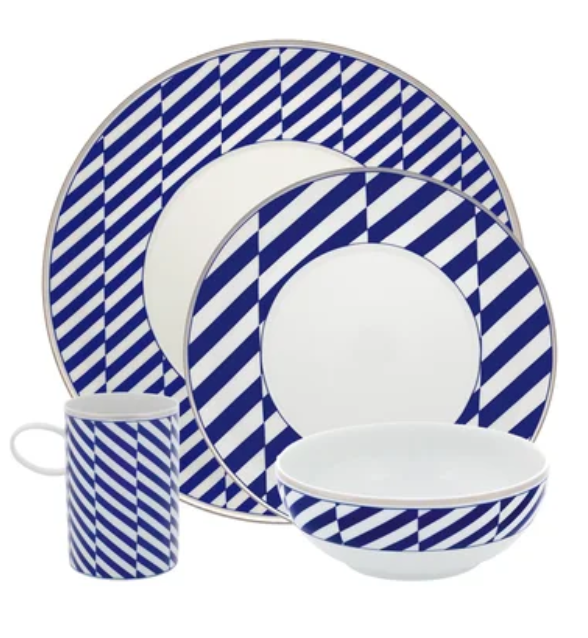 The Harvard Dinnerware set by Vista Alegre includes a mug, bowl, salad plate, and dinner plate, each adorned with bold blue and white diagonal stripes inspired by classic New England style.