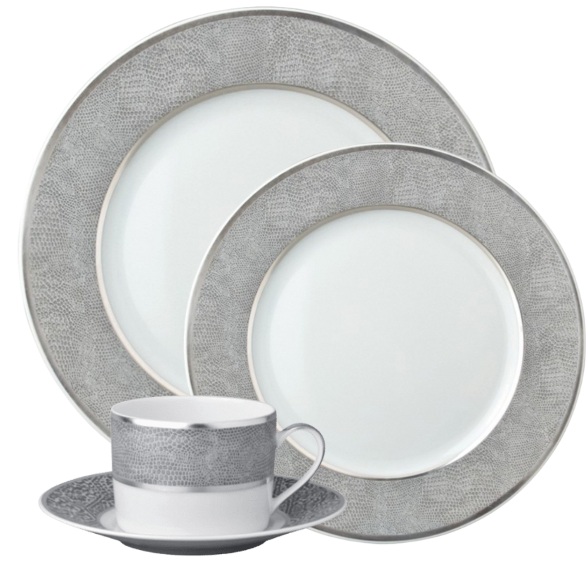 The Bernardaud Sauvage Grey & Platinum dinnerware set in Limoges porcelain includes a dinner plate, salad plate, bread plate, teacup, and saucer with a silver snakeskin-embossed border, white center, and thin platinum rim.