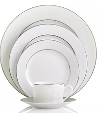 The Bernardaud Dune Dinnerware set includes five fine china pieces—dinner plate, salad plate, bread plate, saucer, and teacup—in white with textured lines and silver rims, all neatly stacked.