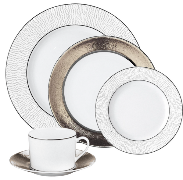 Bernardaud’s Dune Dinnerware set includes a dinner plate, salad plate, bread plate, and teacup with saucer—each crafted in white Limoges porcelain with textured or metallic silver rims.