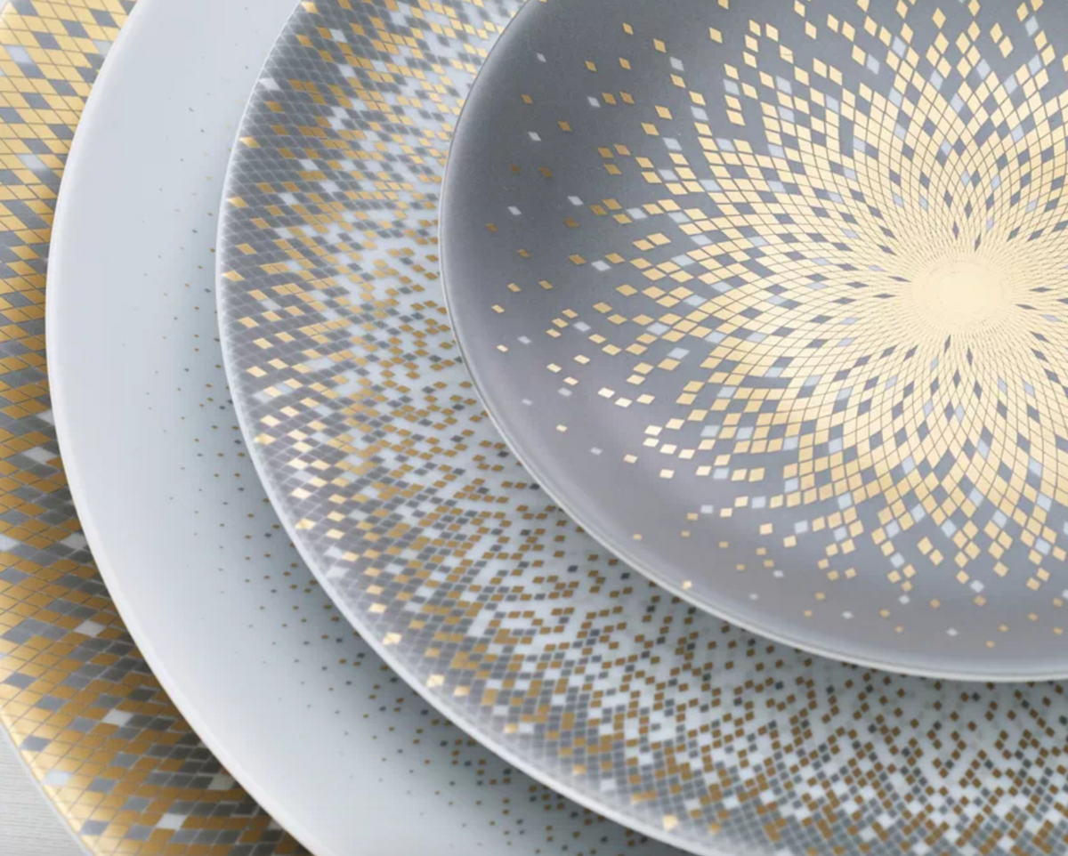 Four overlapping Haviland Souffle D'or Limoges porcelain plates, arranged from largest to smallest, feature intricate gold and silver concentric squares and dotted geometric patterns radiating from the center.