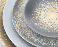 Four overlapping Haviland Souffle D'or Limoges porcelain plates, arranged from largest to smallest, feature intricate gold and silver concentric squares and dotted geometric patterns radiating from the center.