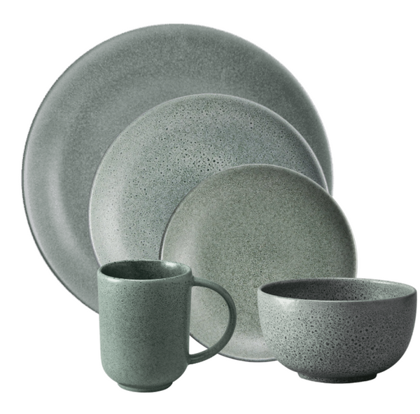 The L'Objet Terra Seafoam Dinnerware set in muted green features a dinner plate, salad plate, bowl, and mug with a speckled matte finish and minimalist design, arranged overlapping each other.