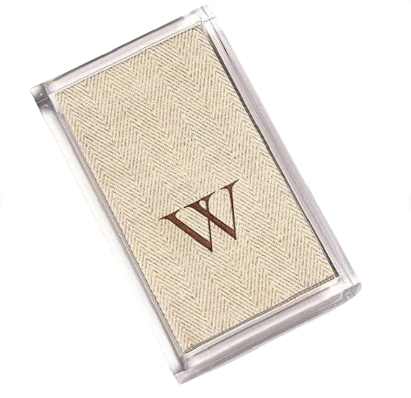 The Caspari Acrylic Guest Towel Holder displays a rectangular beige fabric card with a subtle herringbone pattern and bold brown "W," adding a modern touch.