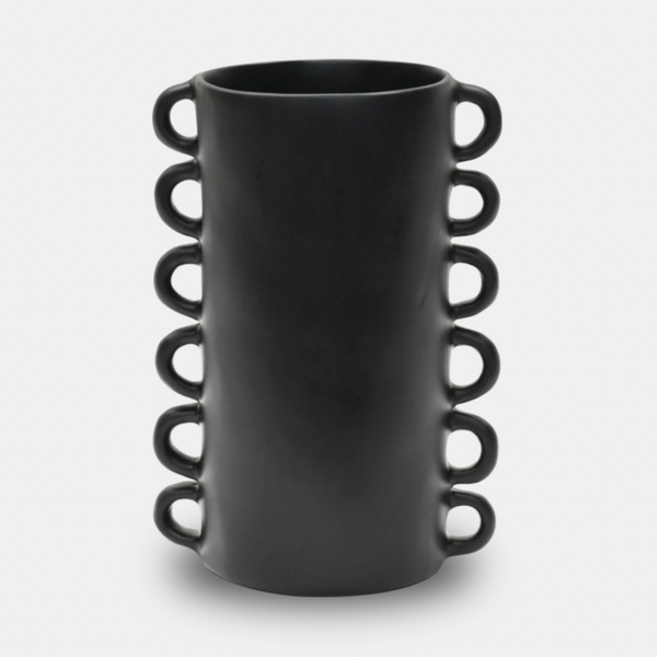 The Tina Frey Loopy Resin Vase Black is a tall, cylindrical vase with a matte finish and six evenly spaced loop handles on each side, shown against a plain white background.