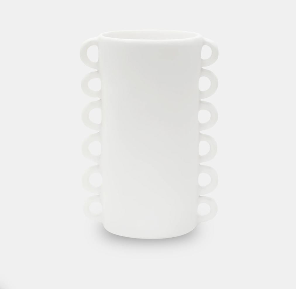 The Loopy Resin Vase White by Tina Frey is a handmade resin vase with a cylindrical shape, scalloped edge, and distinctive looped handles on each side.