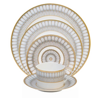 The Philippe Deshoulieres Arcades Gold Dinnerware set includes fine china dinner, salad, dessert, and bread plates plus a teacup and saucer, all adorned with intricate gold and gray geometric patterns.