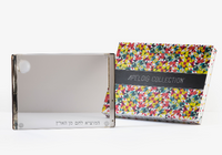 The Personalized Solid Acrylic Challah Board by Apeloig, featuring Hebrew text in the corner, is shown beside a vibrant patterned Apeloig box on a white background.