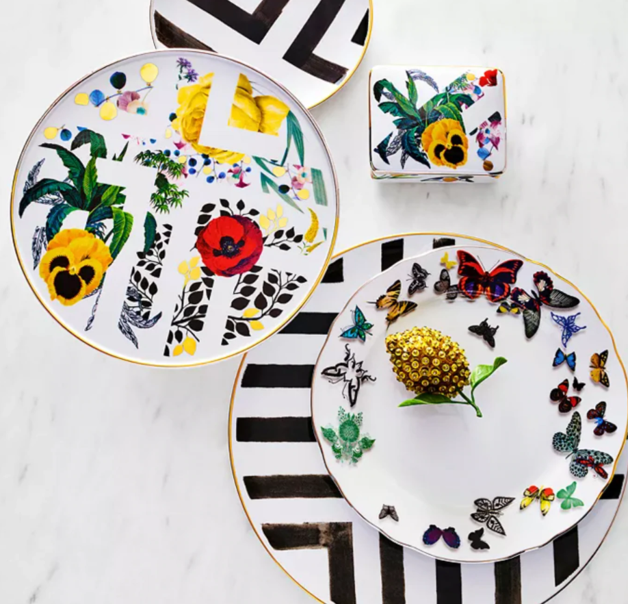 Two porcelain dessert plates and a cup with colorful floral, leaf, butterfly, and bold black geometric designs on white—part of the elegant Primavera Serving Pieces by Vista Alegre.