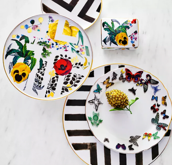 Two porcelain dessert plates and a cup with colorful floral, leaf, butterfly, and bold black geometric designs on white—part of the elegant Primavera Serving Pieces by Vista Alegre.