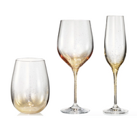 The Kim Seybert Orion Gold Barware Set of 4 includes glassware pieces hand-sprayed with a gold ombré effect and delicate gold flecks, offering elegant style for wine and champagne.