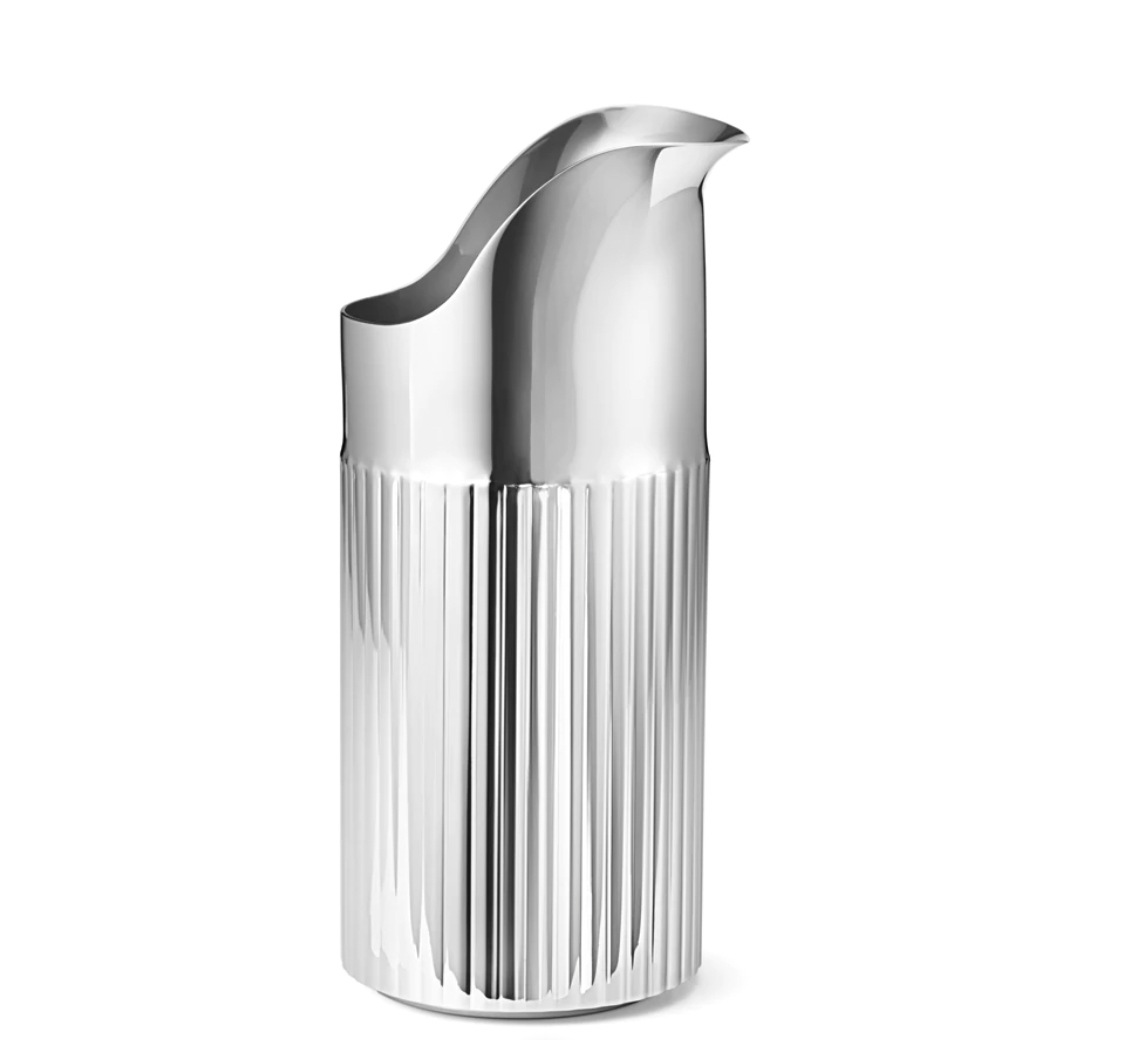 The Georg Jensen Bernadotte Stainless Creamer is a modern, silver milk jug with a ribbed lower half and curved spout, its polished stainless steel surface reflecting light in a stylish design.