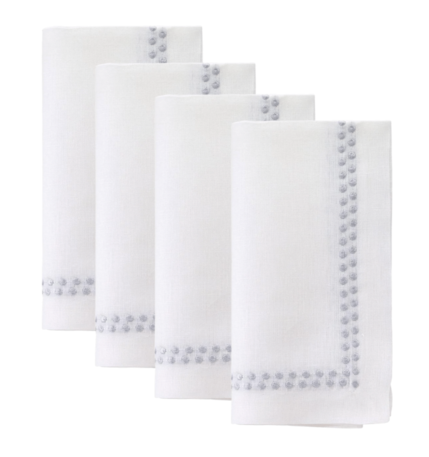 The Bodrum Pearls Napkin Silver Set of 4 features fine linen napkins with embroidered silver dots along two sides, neatly folded and arranged in a staggered row against a white background.