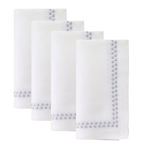 The Bodrum Pearls Napkin Silver Set of 4 features fine linen napkins with embroidered silver dots along two sides, neatly folded and arranged in a staggered row against a white background.