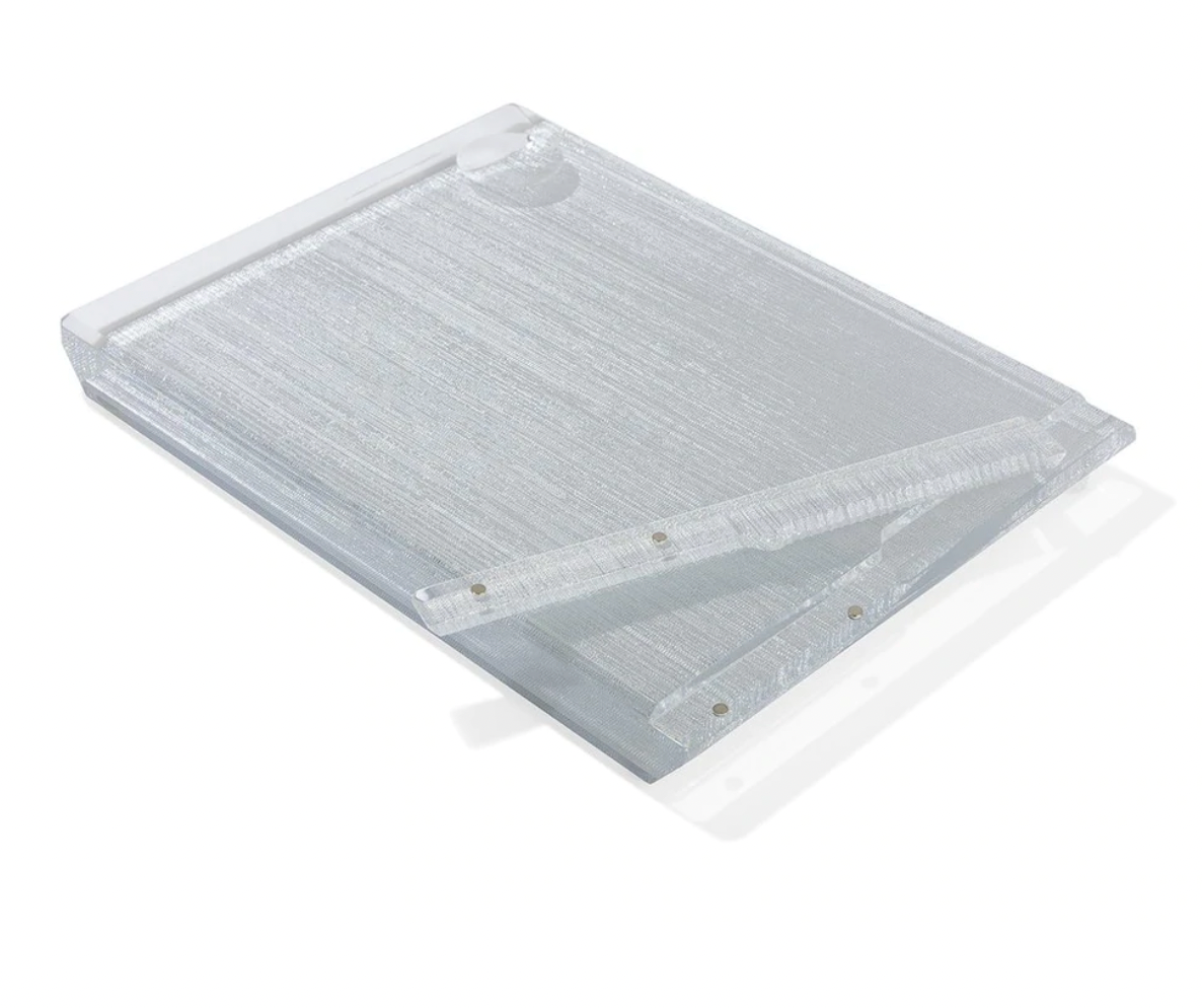 The Apeloig Collection Metallic Silver Acrylic Challah Board features a textured acrylic surface and metal hinge clip, perfectly angled on a white background—ideal as a modern challah board or thoughtful gift.