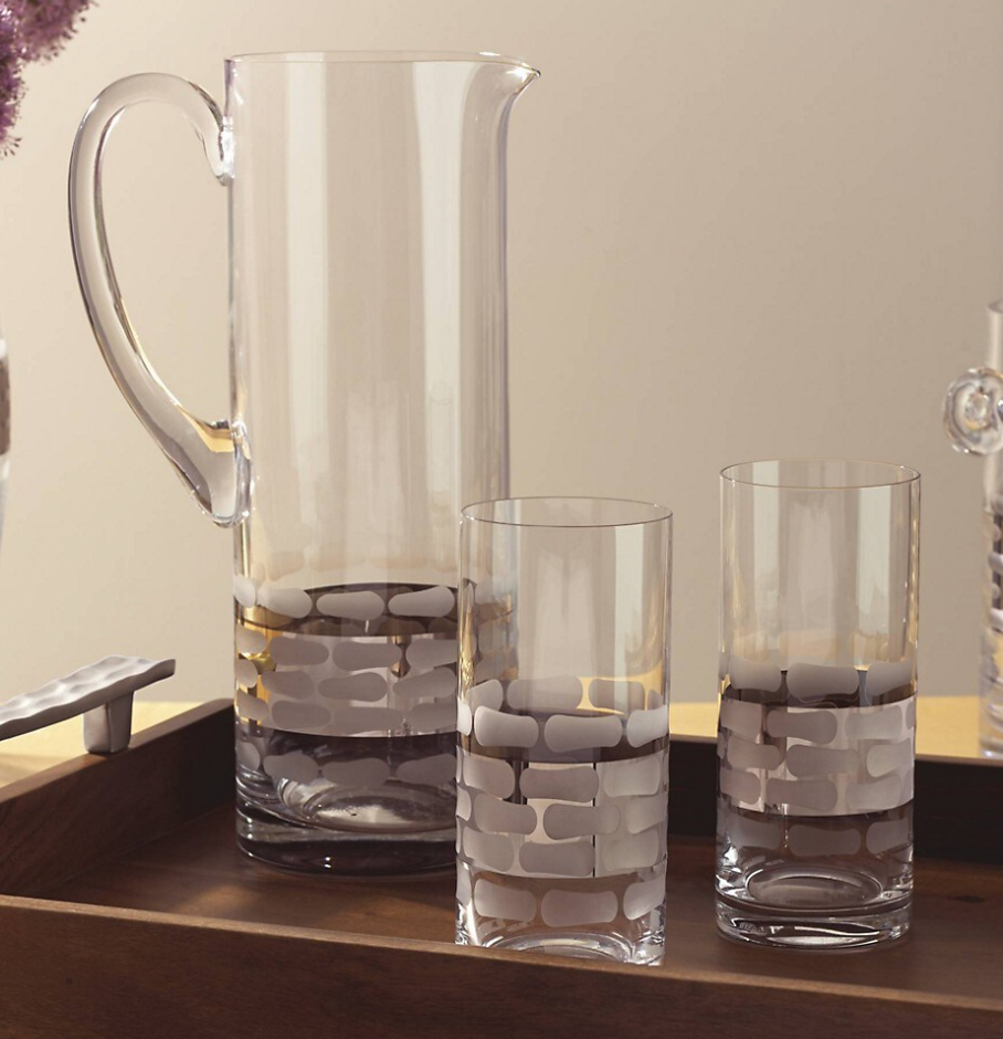 The Michael Wainwright Truro Platinum Pitcher and two matching glasses with a frosted brick pattern rest on a wooden tray against a neutral backdrop.