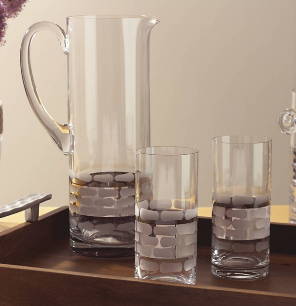 The Michael Wainwright Truro Platinum Pitcher and two matching glasses with a frosted brick pattern rest on a wooden tray against a neutral backdrop.