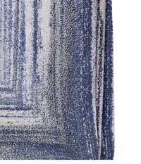 A close-up of the Bodrum Cornice Napkin Navy Set of 4 shows a textured blue and white napkin with a faded gradient pattern, visible woven fibers, and a subtle metallic border along one edge, slightly folded over.