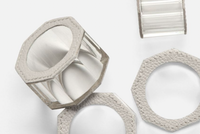 The Arthur Leather Grey Napkin Ring Set of 4 by Blue Pheasant showcases hexagonal clear and textured gray crystal napkin rings with leather-like borders, elegantly arranged to highlight their detailed design and luxury table decor appeal.