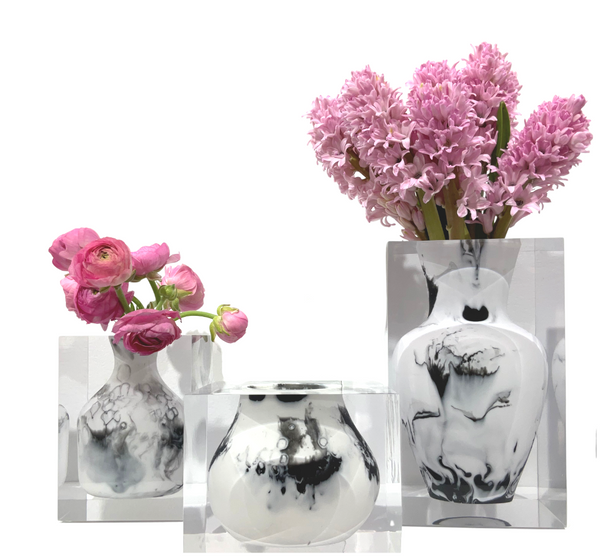 The JR William Lucite Vase Collection features three luxury acrylic resin vases; the tallest displays hyacinths, the middle holds a ranunculus, and the smallest is empty—arranged on a white background for a modern look.