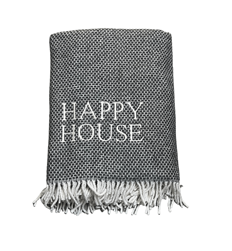 The Happy House Throw by A Soft Idea is a black and white woven blanket with white fringe and "HAPPY HOUSE" embroidered on the front. This home exclusive is machine washable for easy care.