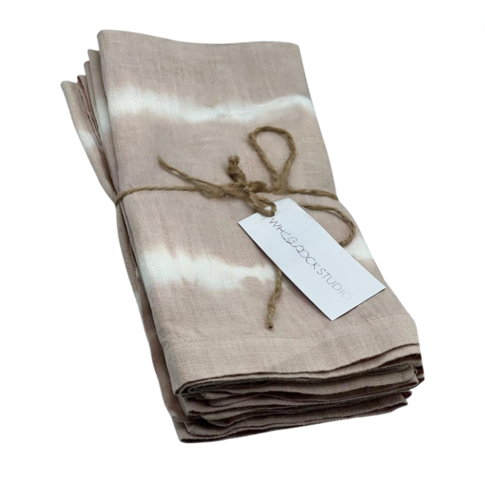 A set of four hand dyed linen napkins in dusty rose by Whigstock Studio, folded and tied with brown twine, includes a white tag—ideal for those who value sustainable essentials.