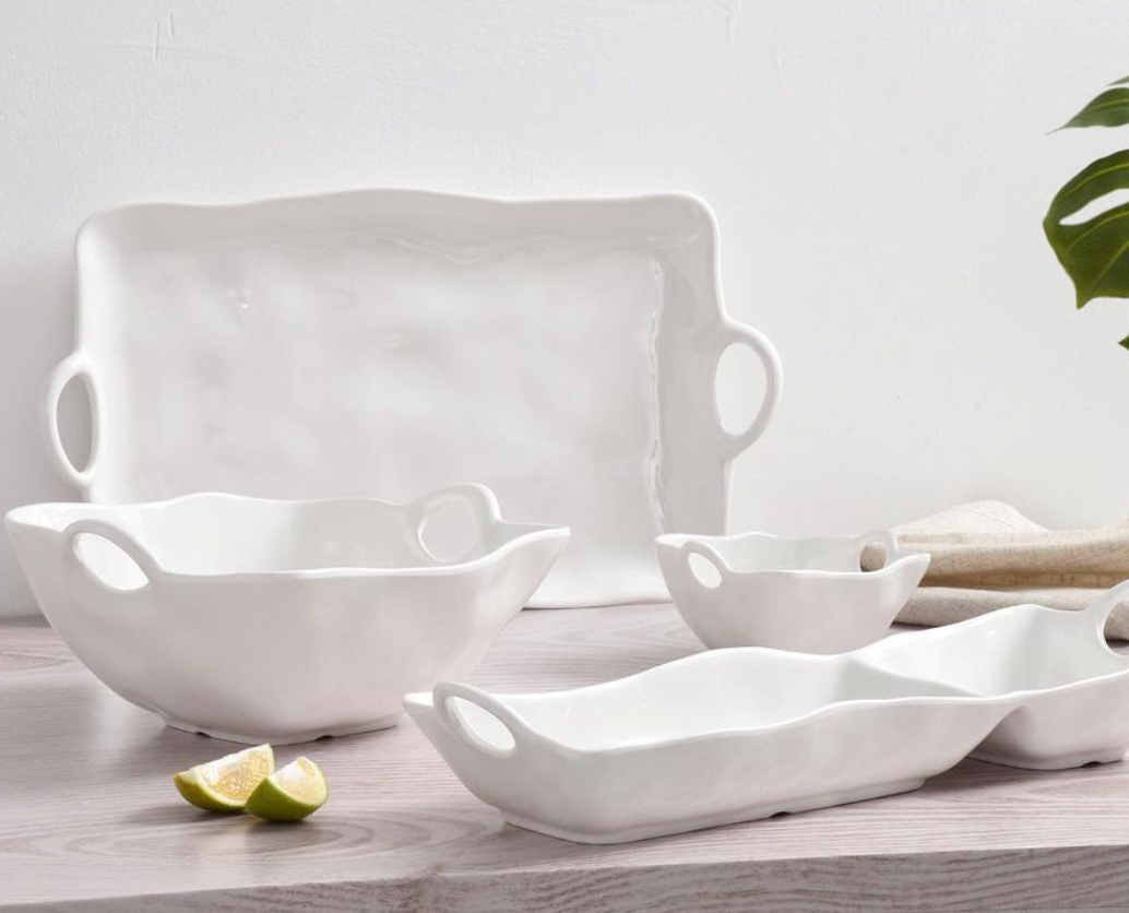 The Ivy Melamine Chip & Dip by PAMPA BAY features white shatterproof dishes with wavy edges and handles, shown on a light wood surface with linen, greenery, and lime wedges. Ideal for outdoor serving at any occasion.